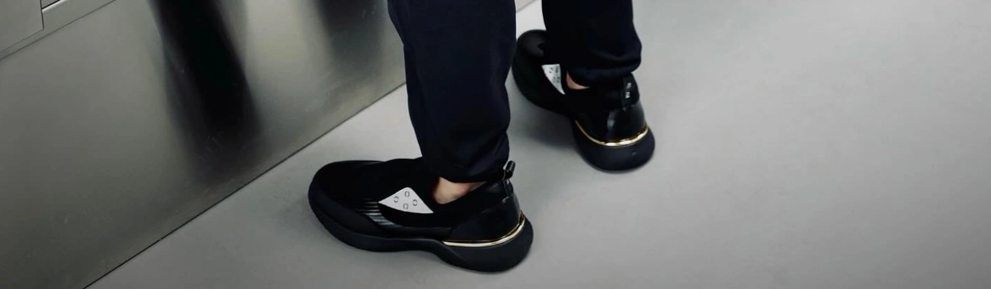 A close-up view of a person wearing black Snogs shoes, walking on a modern, clean floor.