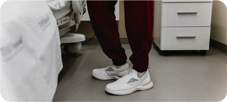 A person wearing white Snogs Dayshift shoes in a medical environment.