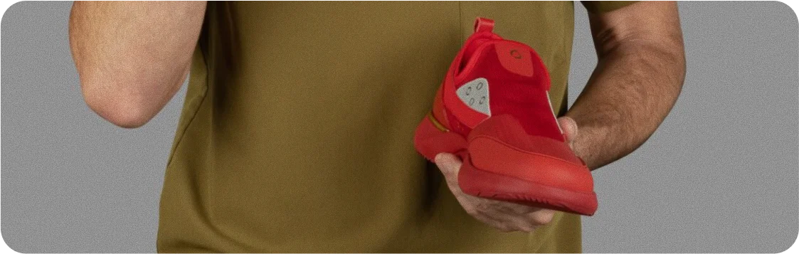 A person holding a pair of vibrant red Snogs shoes.